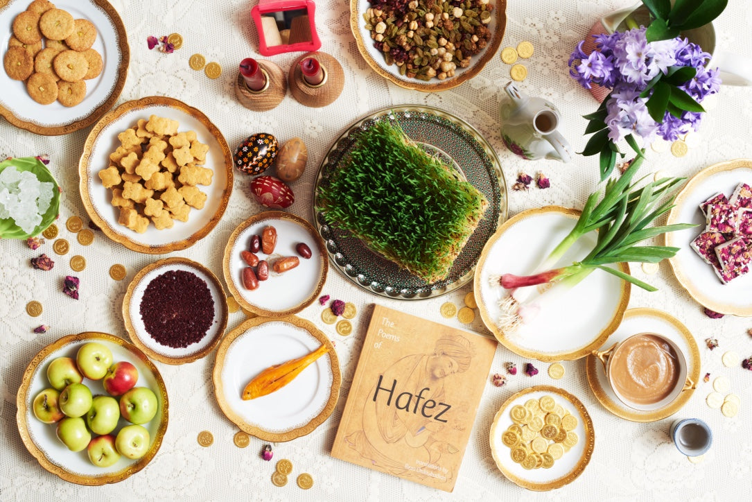 Nowruz table setup featuring chickpea cookies, gold coins, marzipan, dates, flowers and chocolates