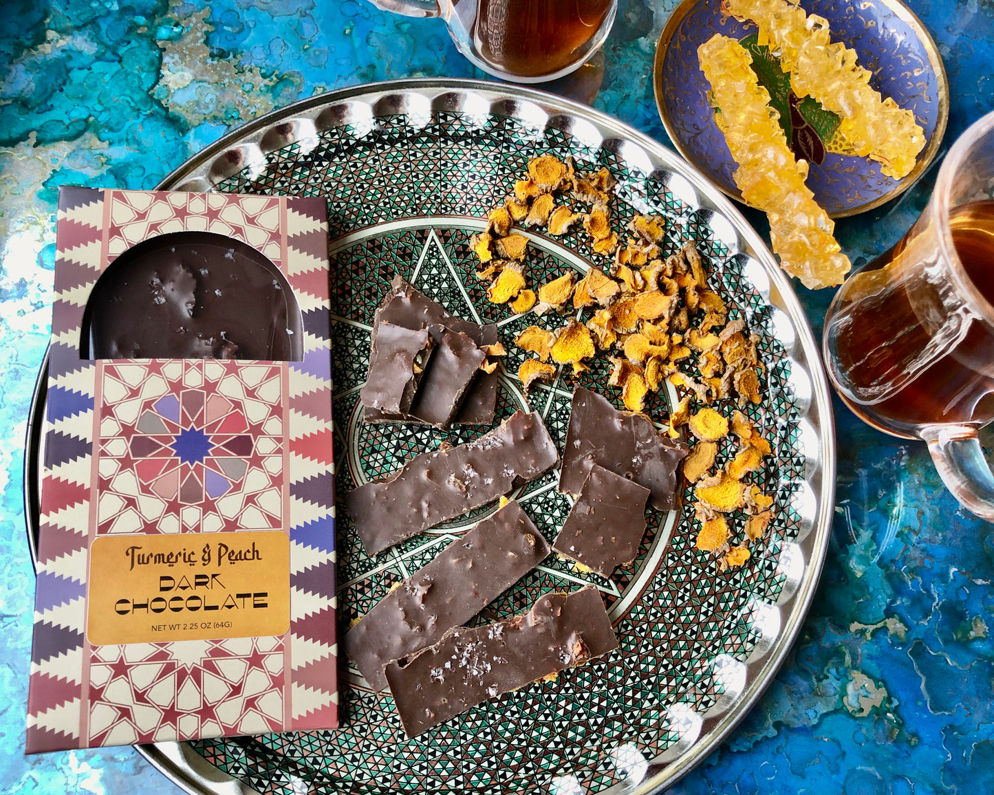 A selection of handcrafted chocolate bars with various toppings and inclusions, including nuts and spices, displayed on a glass plate.