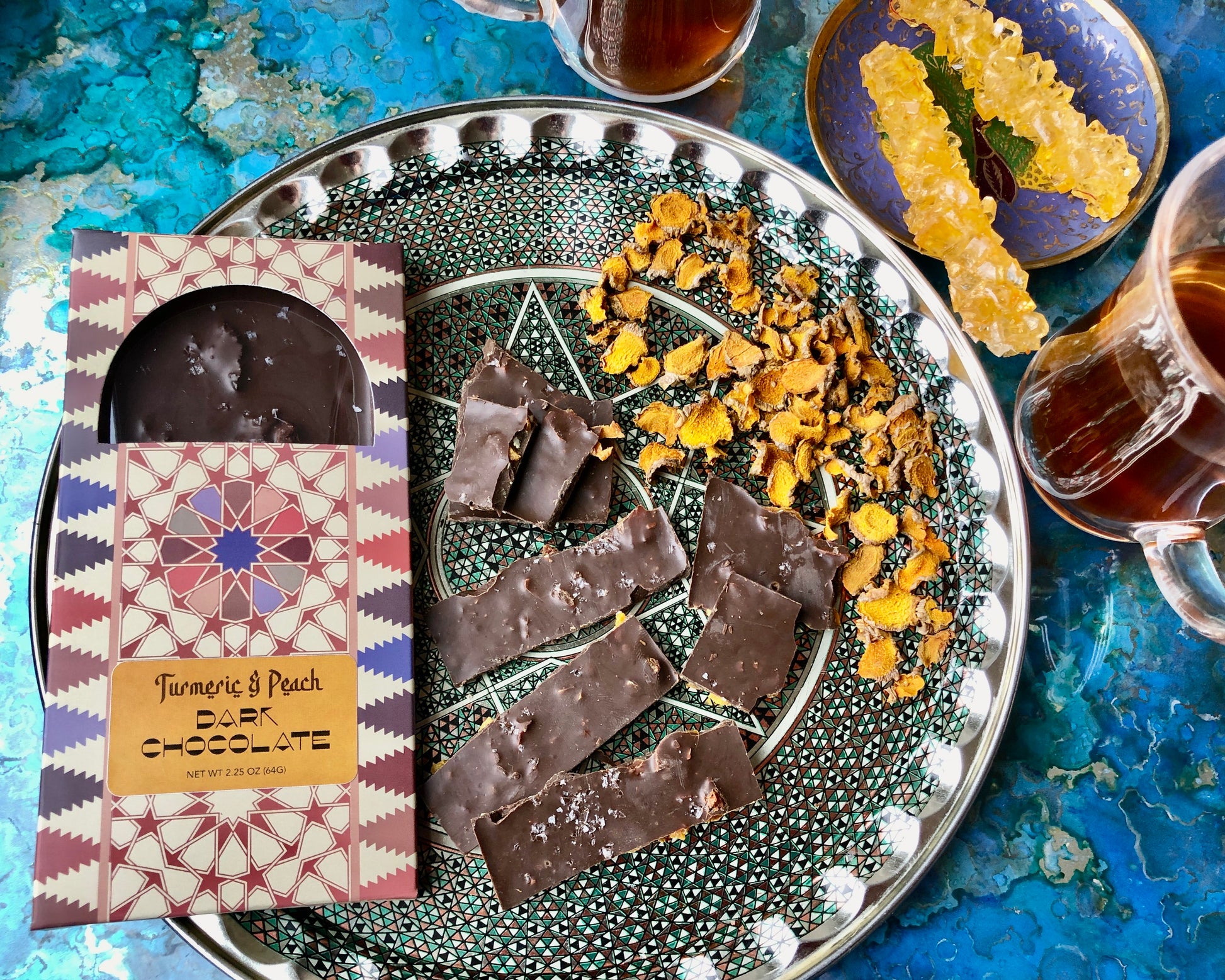 A selection of handcrafted chocolate bars with various toppings and inclusions, including nuts and spices, displayed on a glass plate.