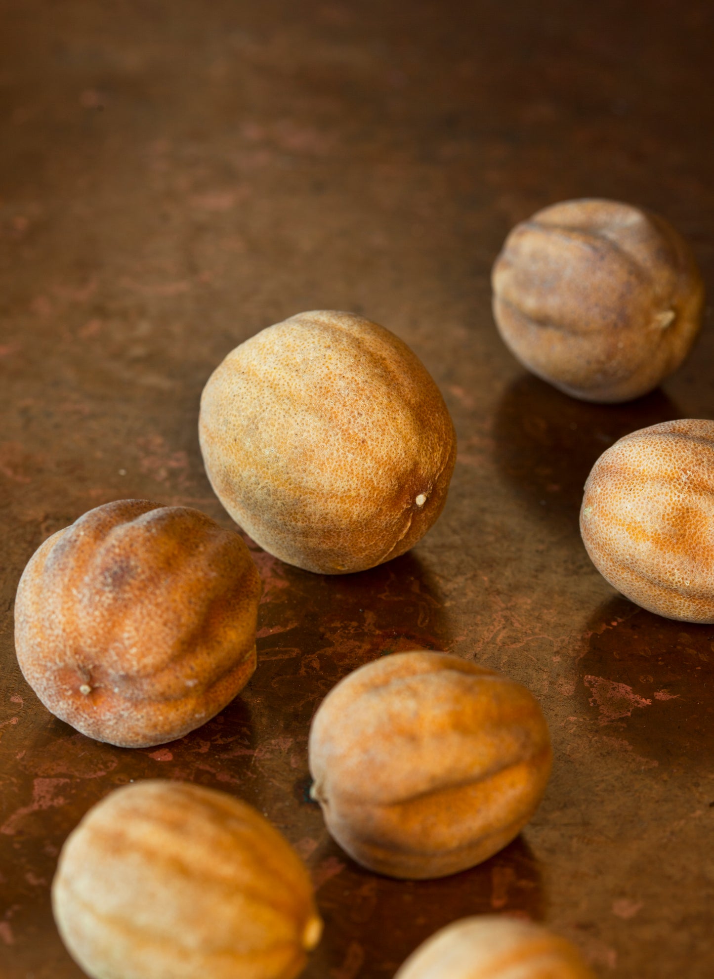 A group of whole dried limes on a brown surface.