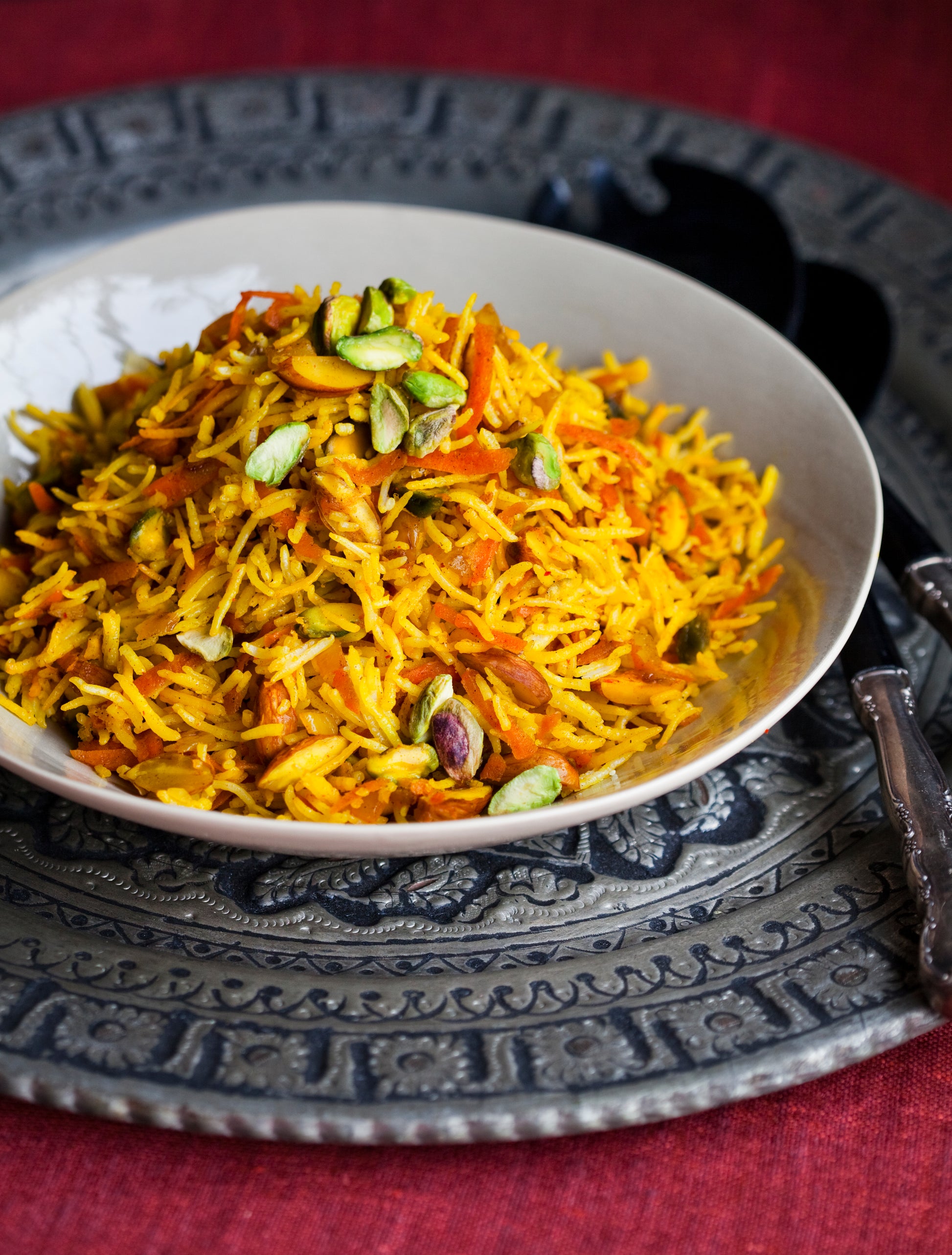 Remington Sweet Rice with pistachios and saffron in a bowl on an ornate background with serving utensils