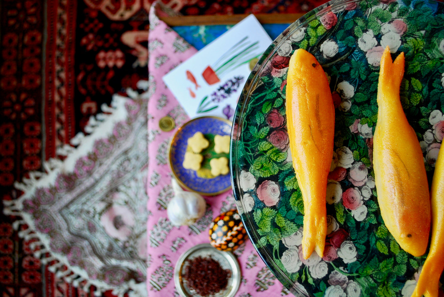 A marzipan goldfish on a plate with Nowruz celebrations in the background, symbolizing the Persian New Year.