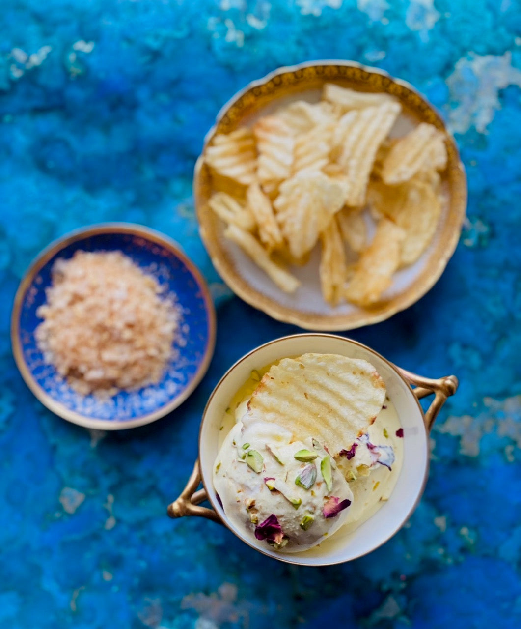 Chips, salt and dip in bowls with blue background